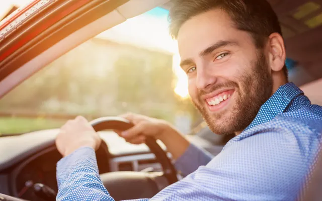 Smiling driver at the wheel of his car on a sunny day
