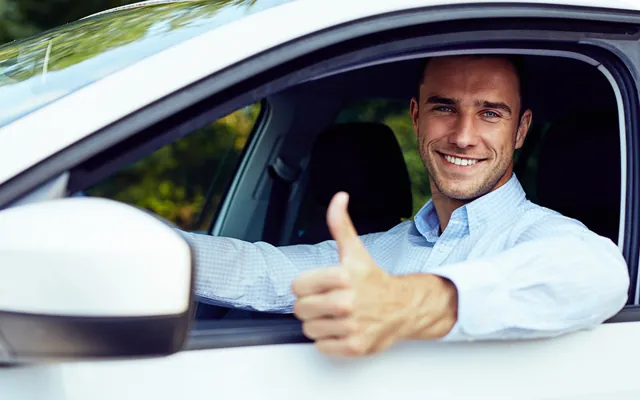 Happy driver giving a thumbs up from his car window, back on the road